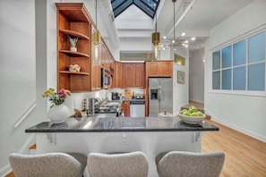 A modern kitchen with a central island, wooden cabinets, and a skylight.
