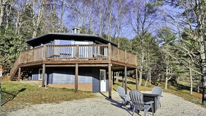 Une cabane avec une terrasse, une table et des chaises.
