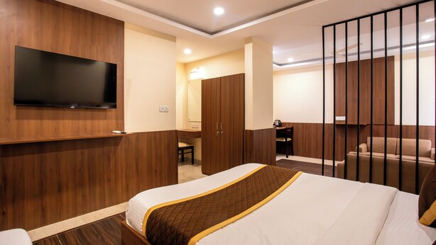 Una camera d'albergo con un letto grande, una TV a muro, una scrivania, una sedia e un divano.