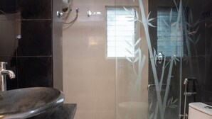 Un bagno moderno con un lavandino freestanding, un water e una zona doccia con pareti in vetro.