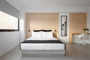 A modern bedroom with a large bed, a wooden slat wall, a desk with a chair, and a mirror. - Syntagma Serenity Suites (Athens)