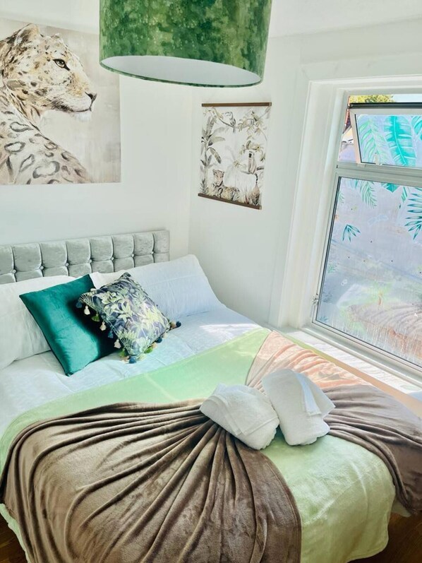 Relax in a serene bedroom with a large bed, tufted headboard, and plush pillows, surrounded by nature views and artwork.