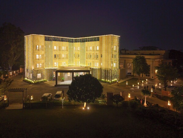 A building with multiple floors, a central entrance, and a surrounding garden area. - HOTEL TATHAGAT ASHOK (Rajgir)