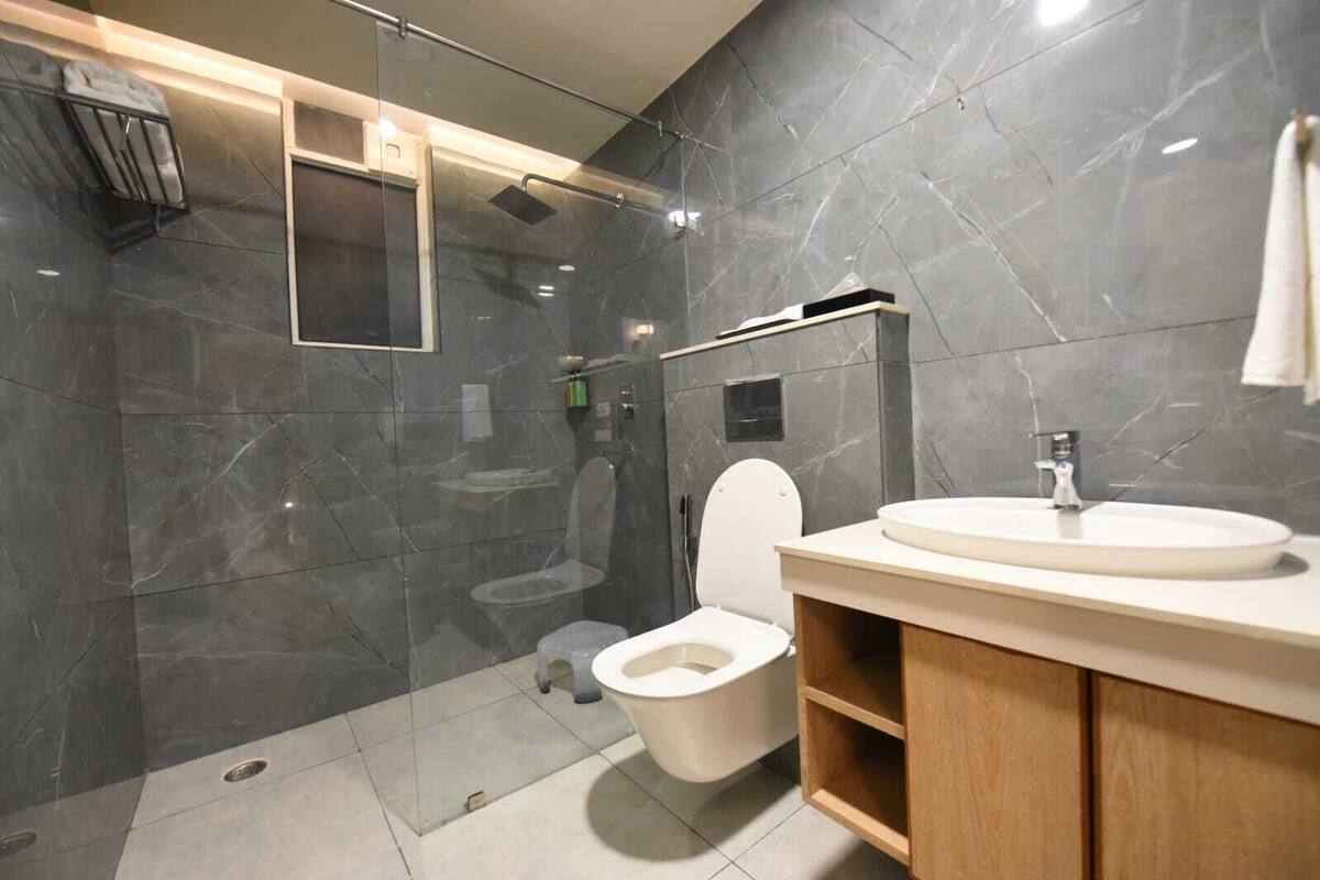 A modern bathroom with a glass-enclosed shower, a white toilet, and a wooden vanity with a sink.