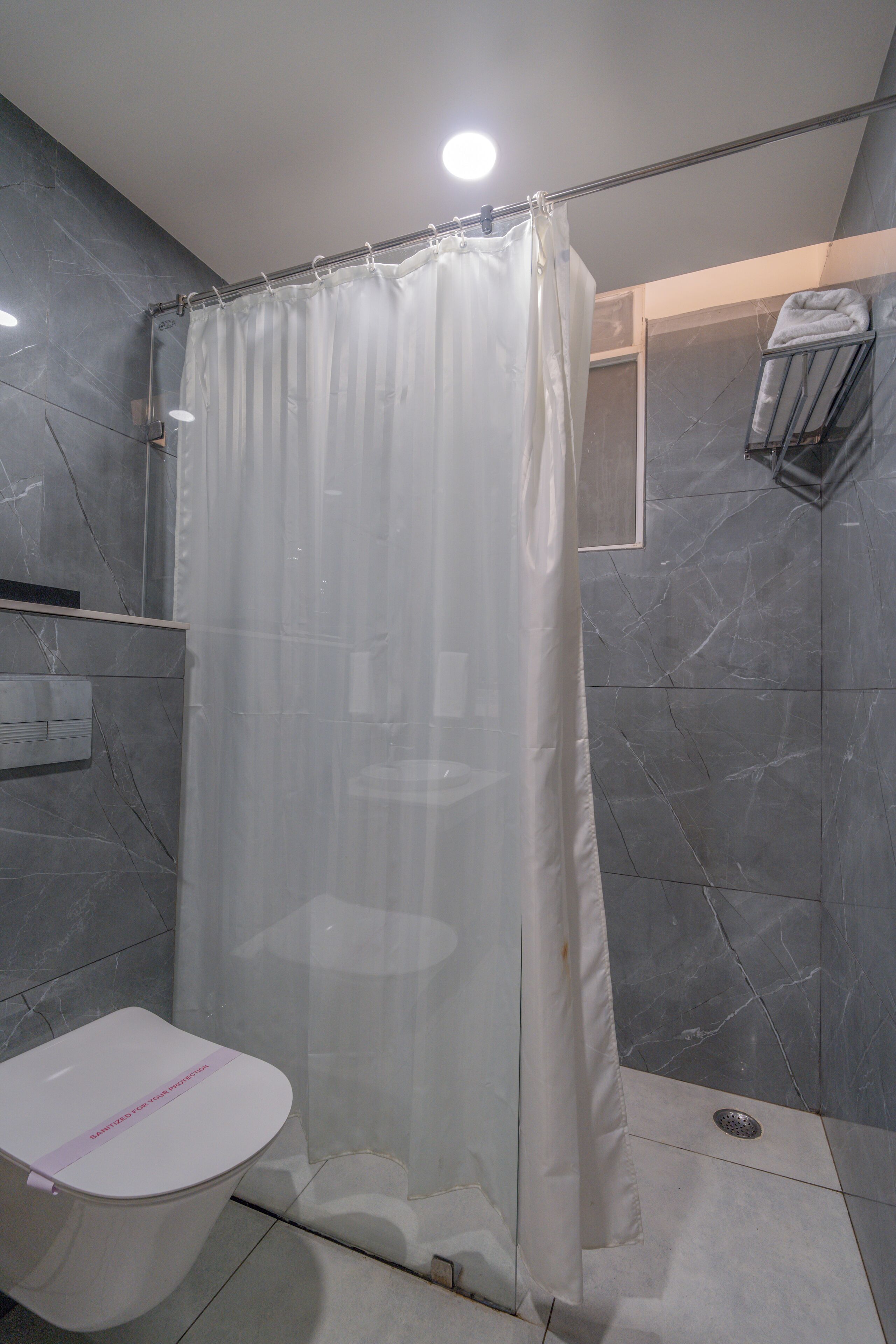 Une salle de bain équipée d’un rideau de douche, de toilettes et d’un porte-serviettes.