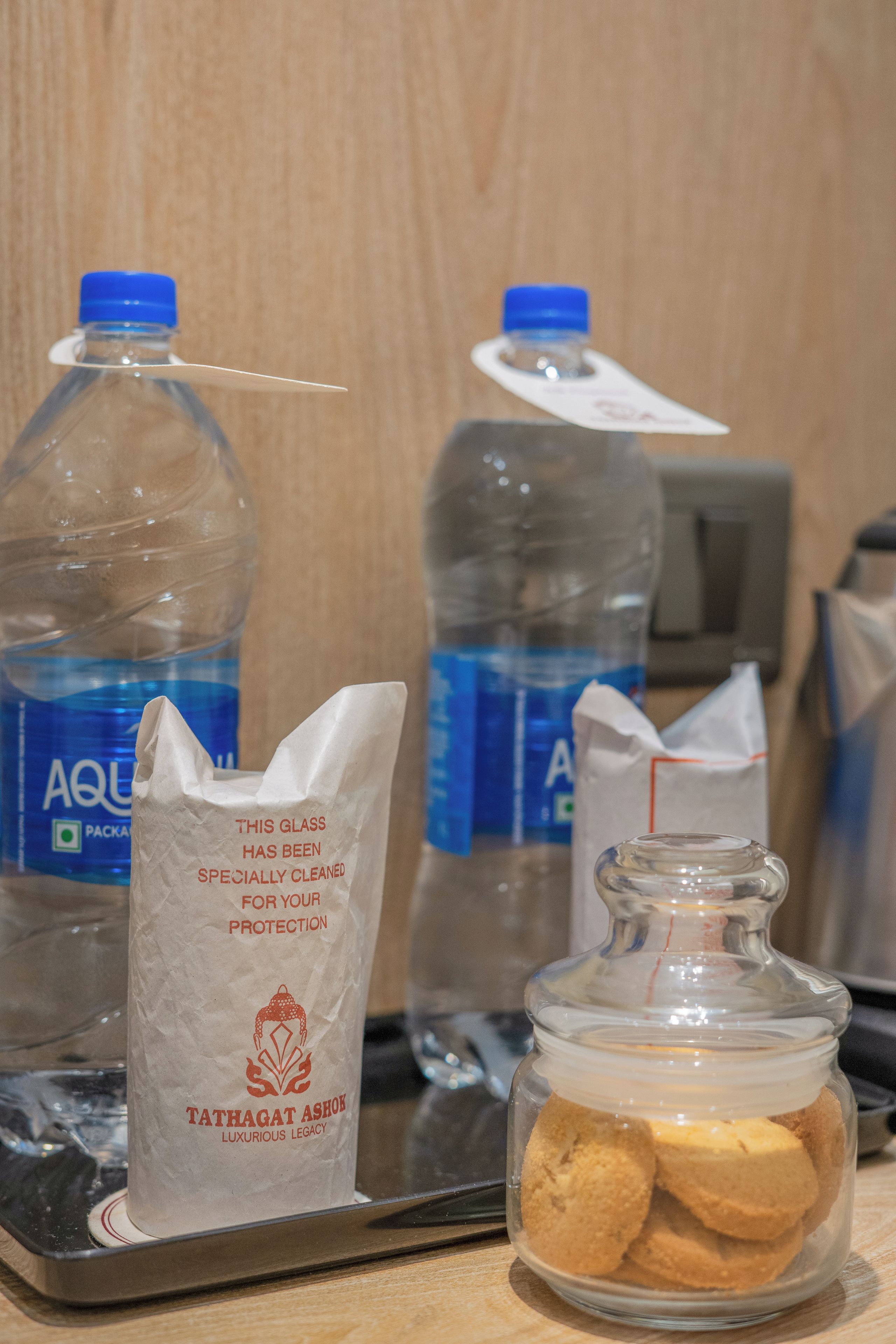 A tray with two water bottles, a tissue, and a glass jar with cookies.