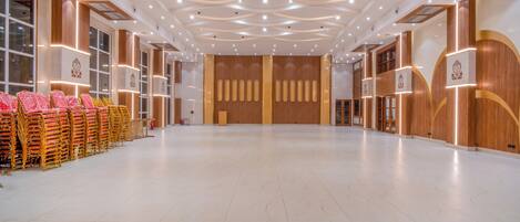 A spacious hall with a high ceiling, rows of chairs on the left, and a large wooden panel wall in the center.