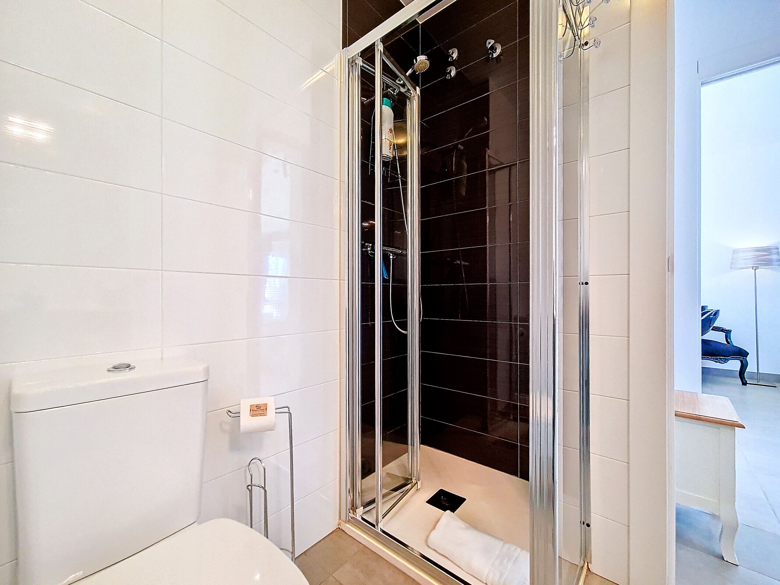 Un baño moderno con ducha de vidrio, inodoro blanco y un perchero para toallas.
