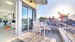 Eine moderne Wohnung mit Balkon, Essbereich und durch Glastüren sichtbarer Küche.