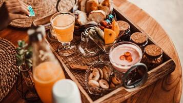 A wooden tray with various food items including bread, nuts, and a glass of orange juice.