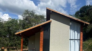A modern house with a sloped roof, large windows, and a covered porch. - Chalé Village Jângal (Machado)