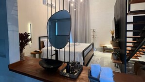 A modern hotel room with a large mirror, a wooden desk, a bed, and a staircase. - Chalé Village Jângal (Machado)