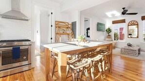 Eine moderne Küche mit Edelstahlbackofen, einem Holzespeisetisch mit Korbstühlen und einer weißen Fliesenspiegel.
