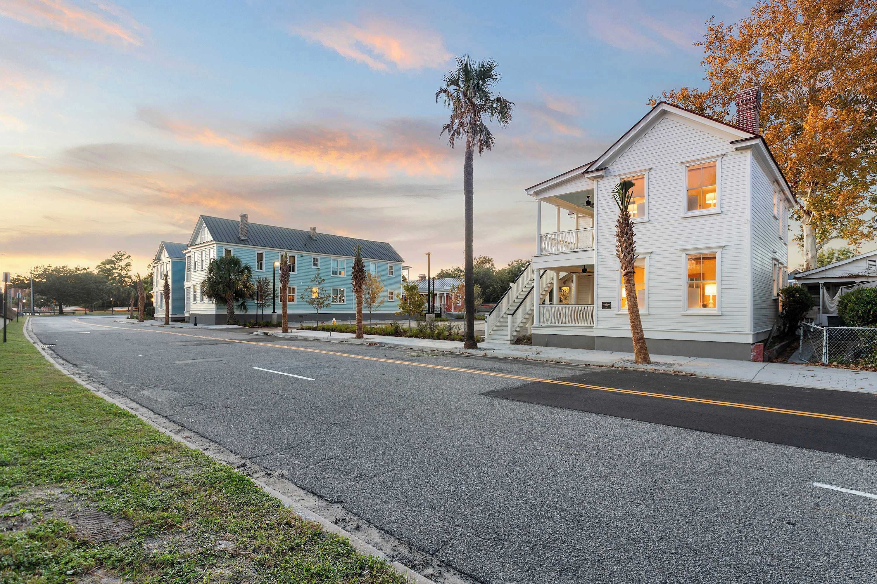 A residential street with houses, a clear sky, and a sunset.