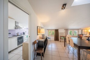A modern kitchen with a stove, oven, and dining area with chairs and a table.
