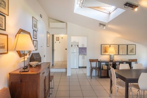 A modern kitchen with white cabinets, a dining area with a table and chairs, and a skylight above.