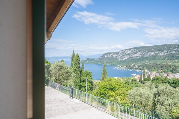 A balcony with a view of a lake, trees, and distant buildings.