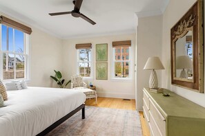 Relax in this serene bedroom with a large bed, comfortable chair, and a dresser with a mirror.