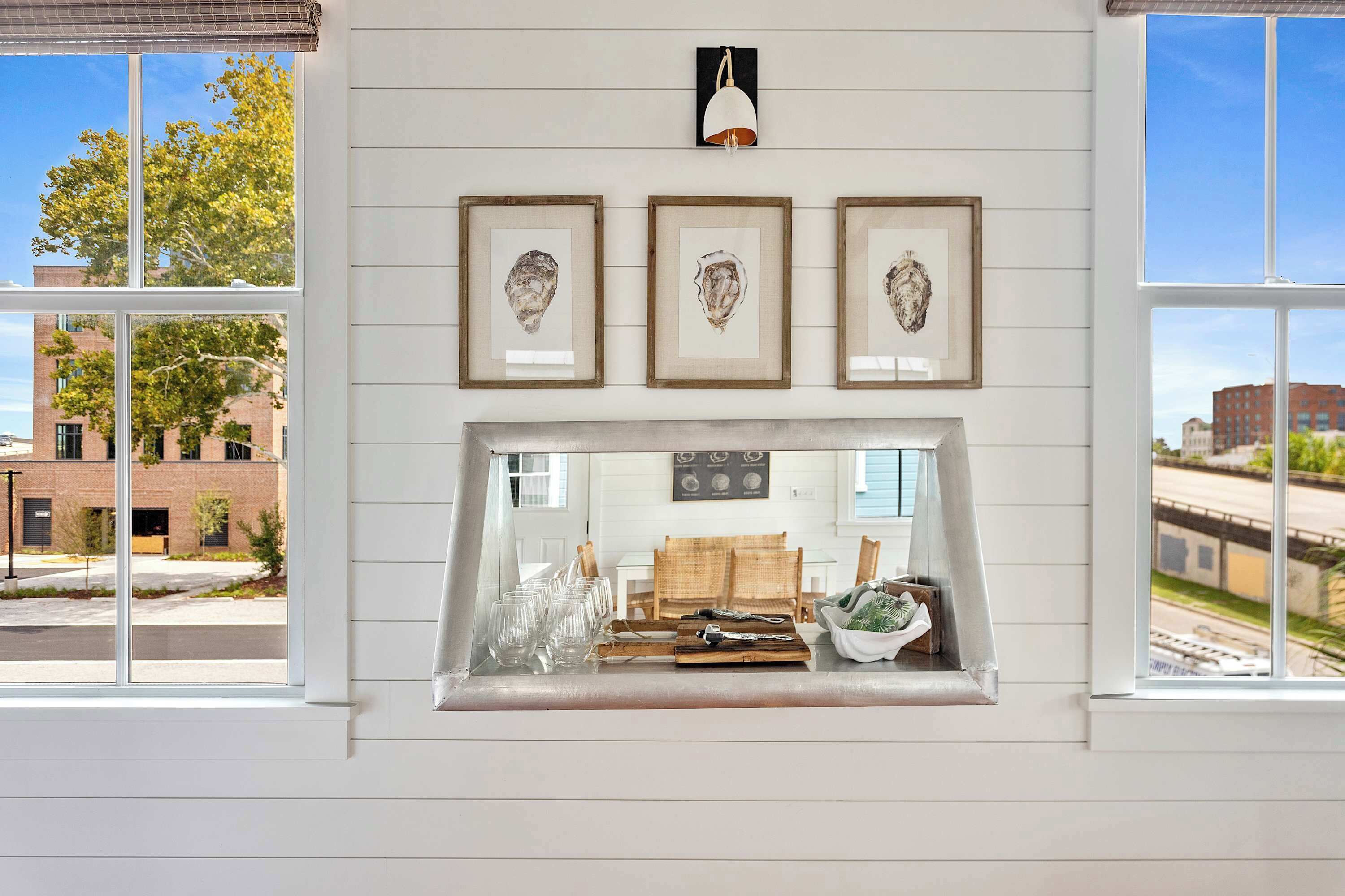 A room with a fireplace, framed artwork, and a view of the street.