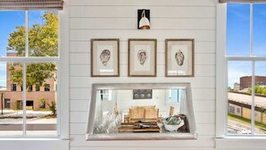 A room with a fireplace, framed artwork, and a view of the street. - Cozy 5BR/5BA Downtown Gem - Close to King! (Charleston)