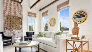 A cozy living room with a white sofa, black leather chairs, a round coffee table, and a rustic wooden side table. - Cozy 5BR/5BA Downtown Gem - Close to King! (Charleston)