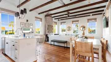 A spacious kitchen with a large island, wooden beams, and a brick wall.