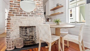 Una habitación acogedora con chimenea de ladrillo, sillones de mimbre blanco y un espejo redondo.