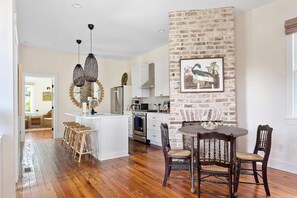 Enjoy meals in the kitchen with an oven and stainless steel refrigerator, surrounded by a rustic brick accent wall and a dining table with dark chairs.