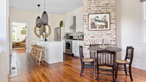 Una cocina moderna con armarios blancos, una pared de ladrillo decorativa y un comedor con sillas de madera.