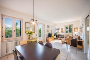 A spacious living area with a dining table, chairs, a sofa, and a television.