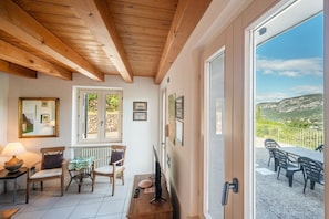 A cozy room with wooden beams, a dining area with chairs, a table, and a TV.