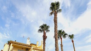 A multi-story building with balconies, palm trees, and a clear sky. - Superb apartment renovated in a quiet area close to everything with  see views (VC)