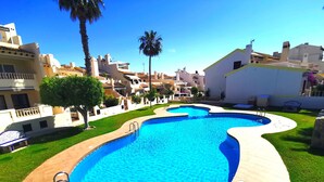 A swimming pool with a curved design, surrounded by a paved walkway and green grass. - Superb apartment renovated in a quiet area close to everything with  see views (VC)