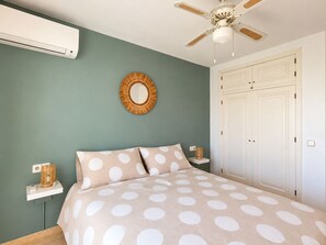 A bedroom with a bed, a ceiling fan, a wall-mounted mirror, a wardrobe, and a bedside table with a lamp. - Superb apartment renovated in a quiet area close to everything with  see views (VC)