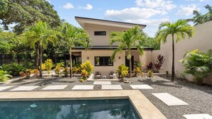 A modern house with a swimming pool, surrounded by tropical plants and a clear sky. - Brand New Tropical Oasis Expansive Outdoor Space (Playa Langosta)