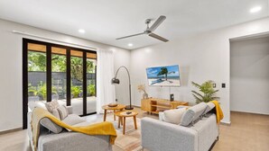 A modern living room with a sofa set, a TV, a ceiling fan, and a view of the outdoors. - Brand New Tropical Oasis Expansive Outdoor Space (Playa Langosta)