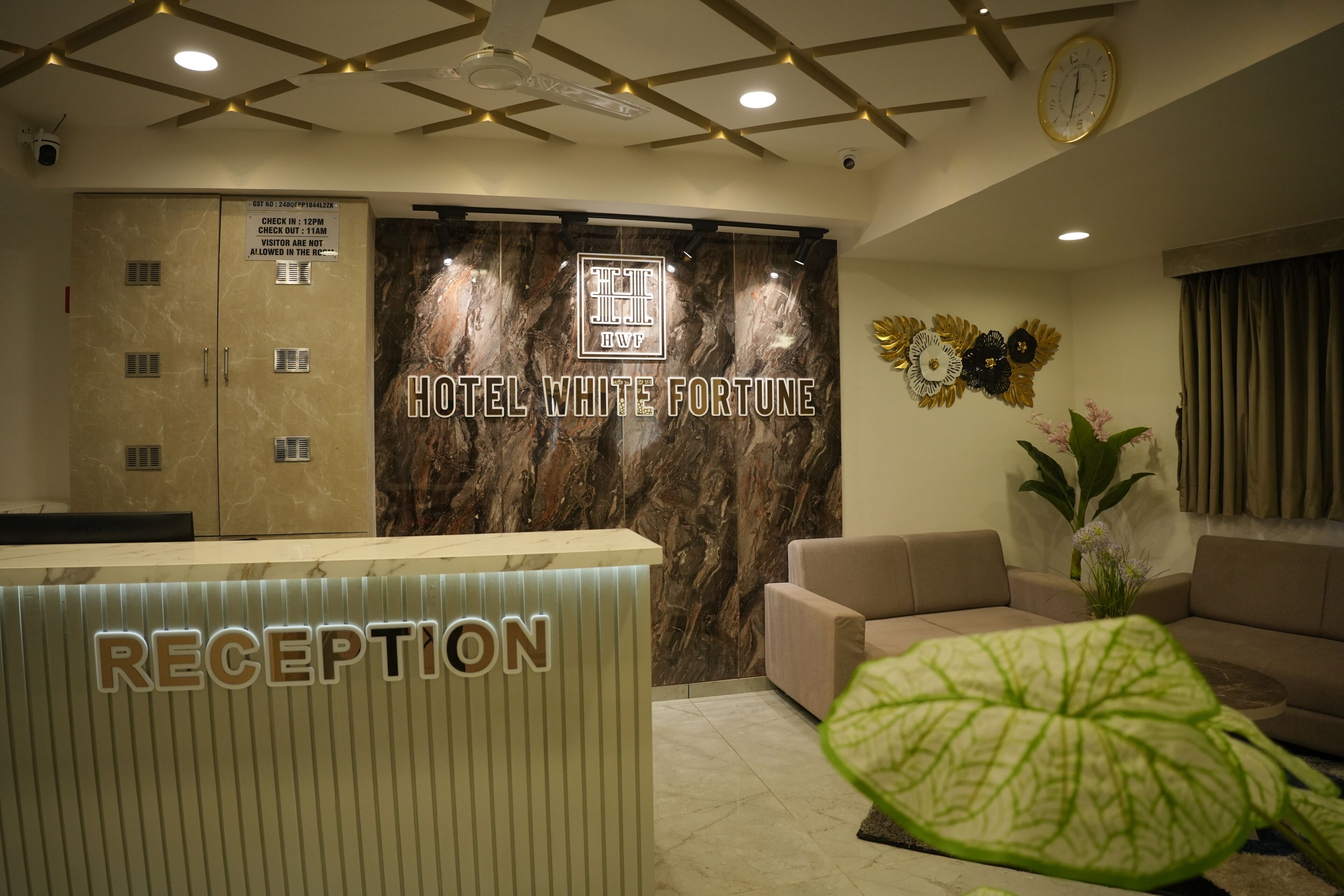 A hotel reception area with a marble wall, a clock, and a reception desk labeled "RECEPTION".