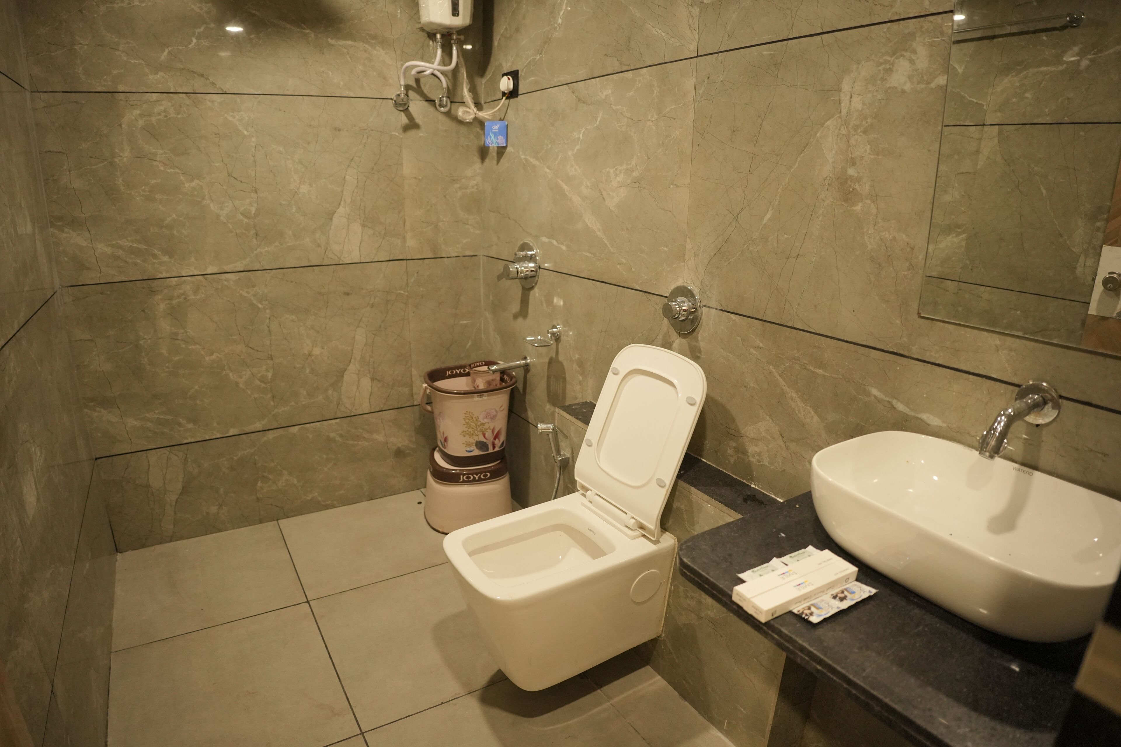 A bathroom with a toilet, sink, and marble walls.