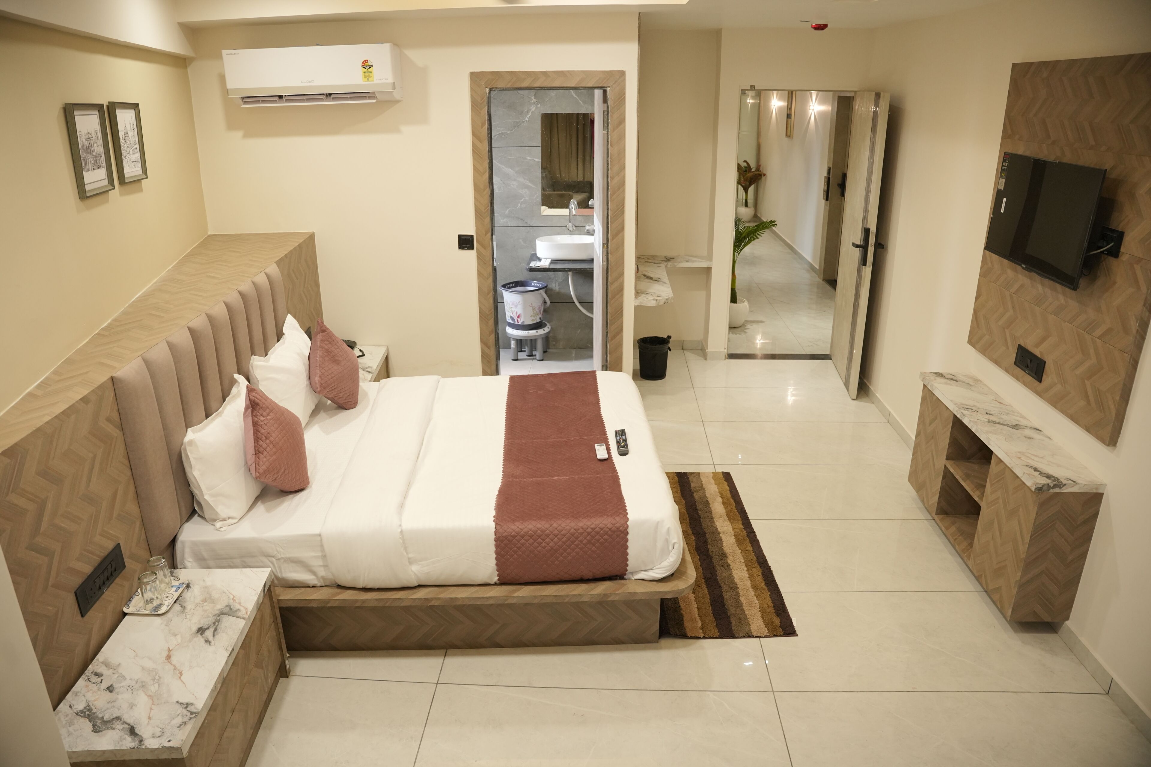 A hotel room with a bed, bedside table, TV, and a bathroom visible through an open door.