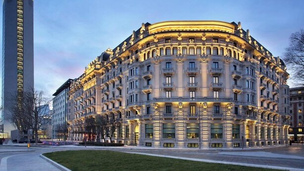 A grand, multi-story hotel with classical architecture, featuring a curved facade and multiple balconies.