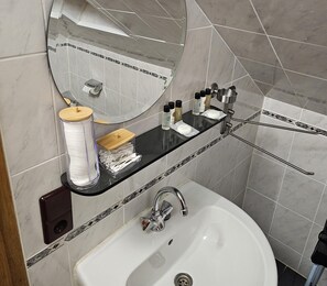 A bathroom with a white sink, a mirror, and toiletries on a black shelf. - Wine Country Apartment (Veldenz)