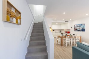 A staircase leading to a dining area with a table and chairs, a kitchen in the background, and a painting on the wall. - Amazing Between Two Seas by Fidalsa (Murcia)