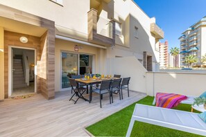 A modern apartment with a dining area, a balcony with a sofa, and a view of other buildings. - Amazing Between Two Seas by Fidalsa (Murcia)