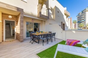 Een modern appartement met een eethoek, een klein balkon en uitzicht op andere gebouwen.