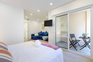 A hotel room with a bed, a sofa, a TV, and a balcony with a table and chair. - Amazing Between Two Seas by Fidalsa (Murcia)