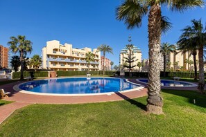 A swimming pool surrounded by palm trees and a multi-story hotel building. - Amazing Between Two Seas by Fidalsa (Murcia)