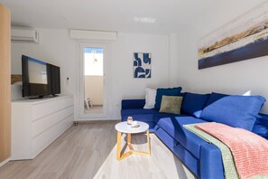 A modern living room with a blue sofa, a small white table, and a flat-screen TV. - Amazing Between Two Seas by Fidalsa (Murcia)