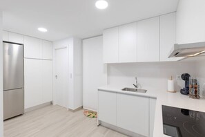 A modern kitchen with white cabinetry, a stainless steel refrigerator, a sink, and a coffee machine. - Amazing Between Two Seas by Fidalsa (Murcia)