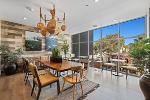 A spacious dining area with a large wooden table, multiple chairs, and a unique rope chandelier.