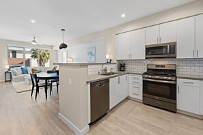 A modern kitchen with white cabinets, a built-in microwave, and a stainless steel oven.